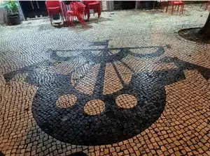 Barco e dois corvos representados na calçada portuguesa em Lisboa.