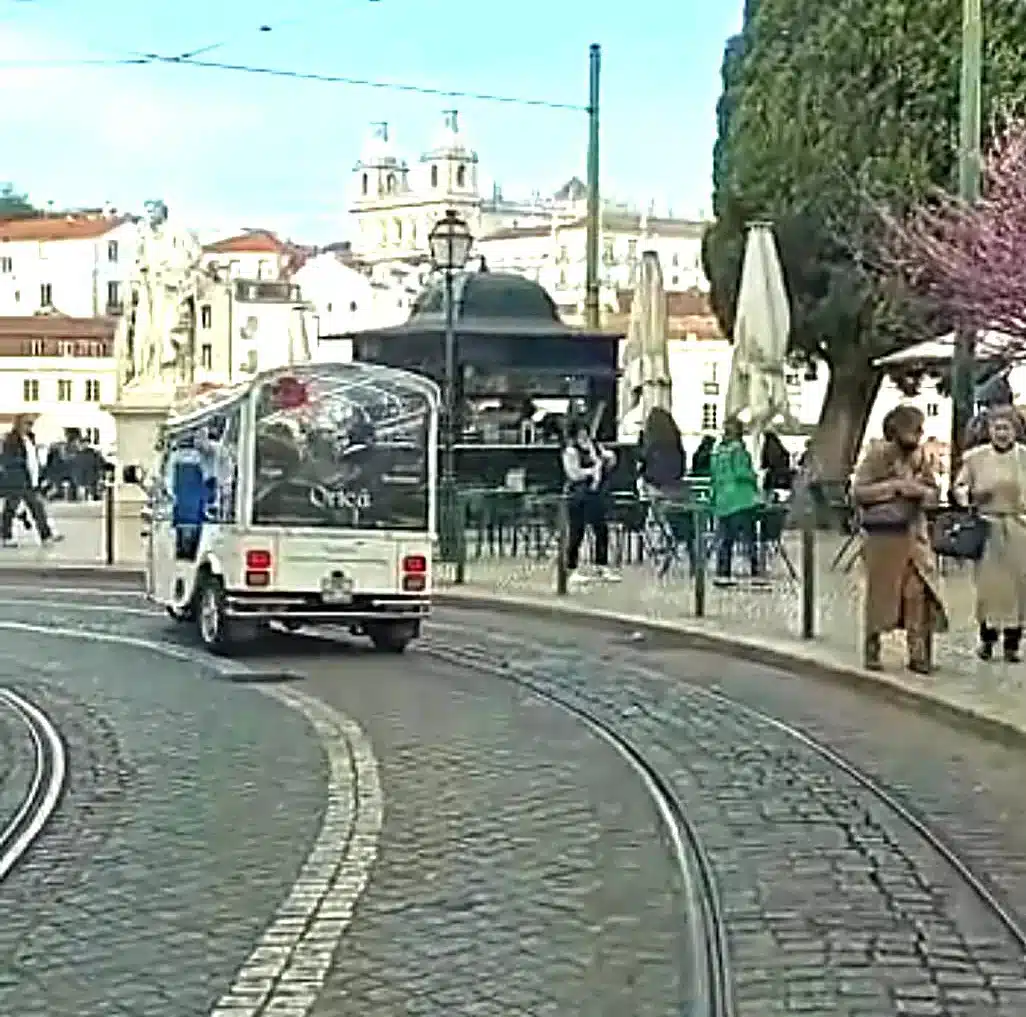 Private tuk tuk tour in Alfama passing Portas do Sol viewpoint with São Vicente Monastery in historic Lisbon.