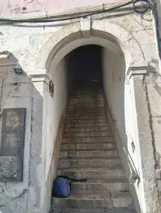 Narrow stone staircase passing through the Postigo da Conceição in Alfama, Lisbon.